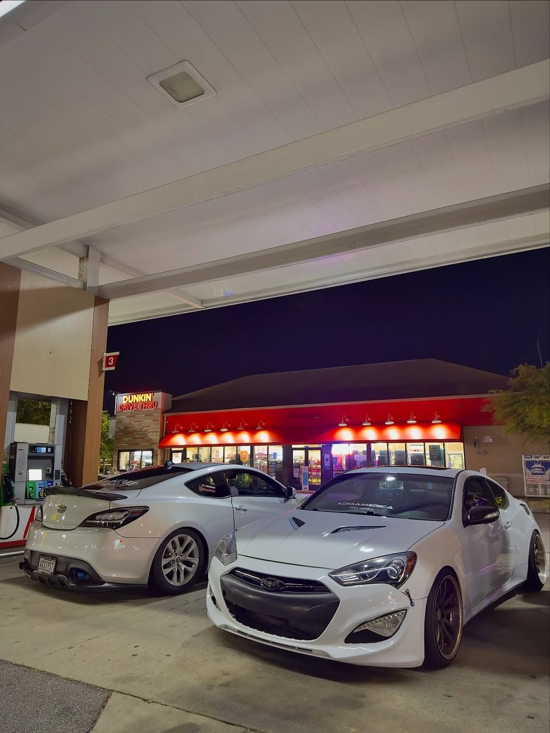 A modified Genesis coupe parked in a roadside setting at dusk with a relaxed editorial composition.