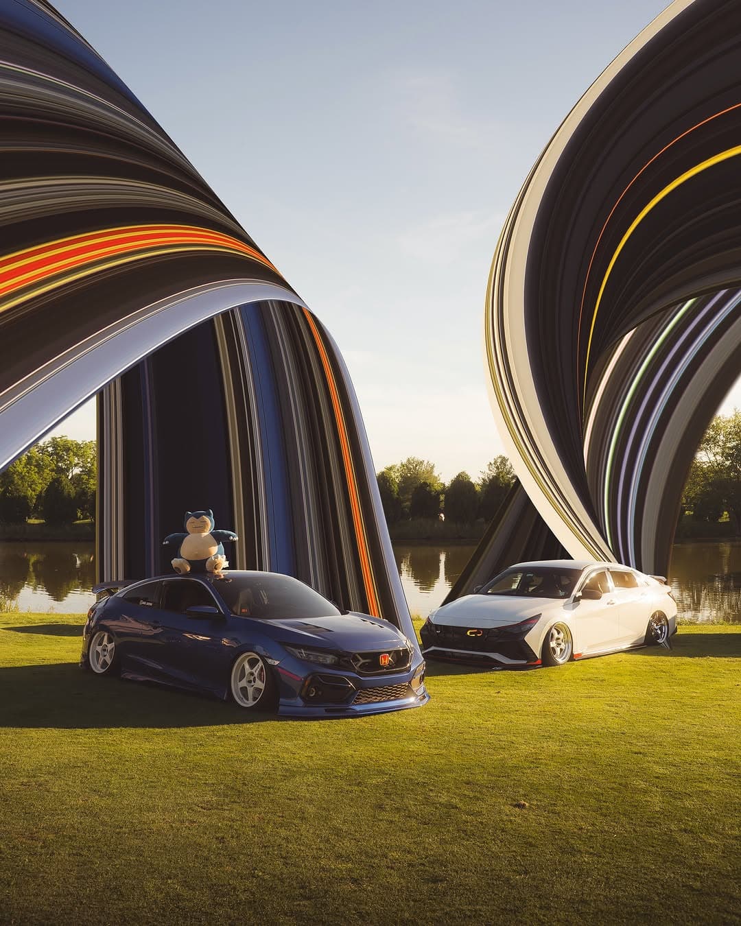 Two modified sedans staged in an edited dual-car composition on a grassy lakeside setting.