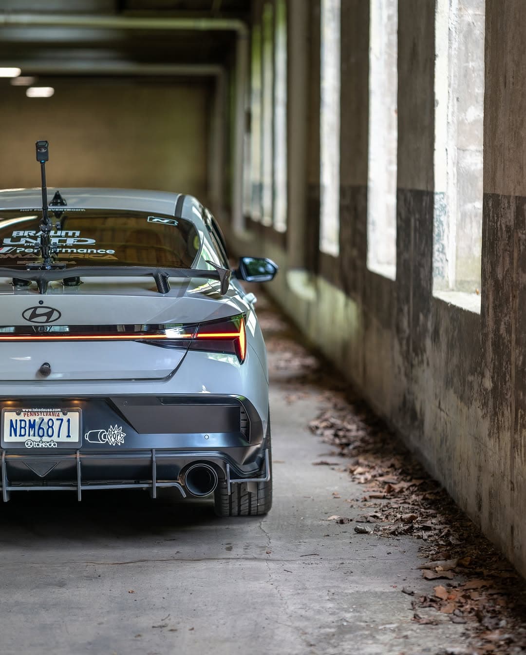 The rear of a silver Hyundai Elantra N photographed inside a concrete tunnel with window light.
